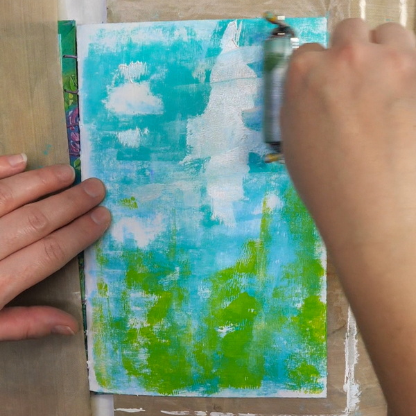 Adding Golden Paint to an art journal page with a brayer
