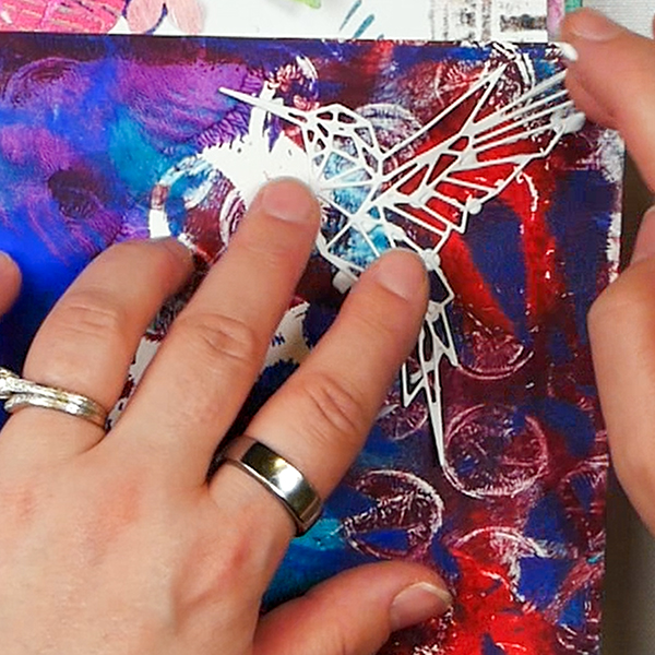 Adding hummingbird cut out to gel plate printed paper