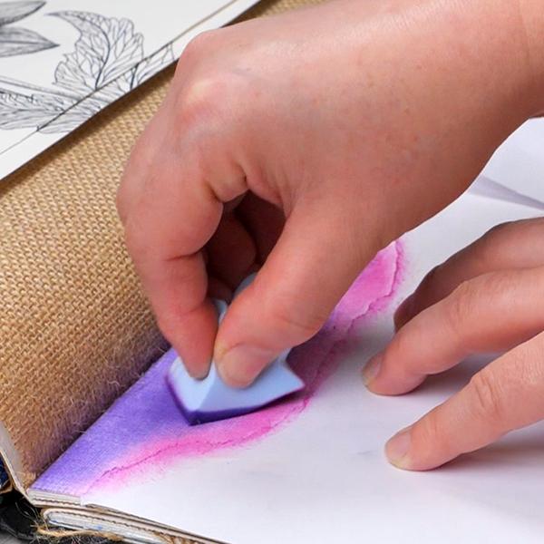 Blending Violet Pan Pastel to create cloud shapes on an art journal page