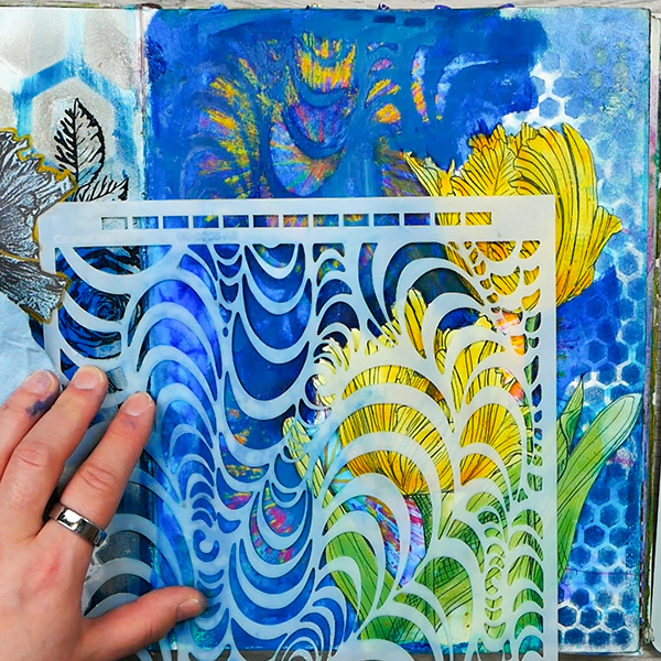 Using stencil and baby wipe to lift paint to create subtractive layers in mixed media art journaling project